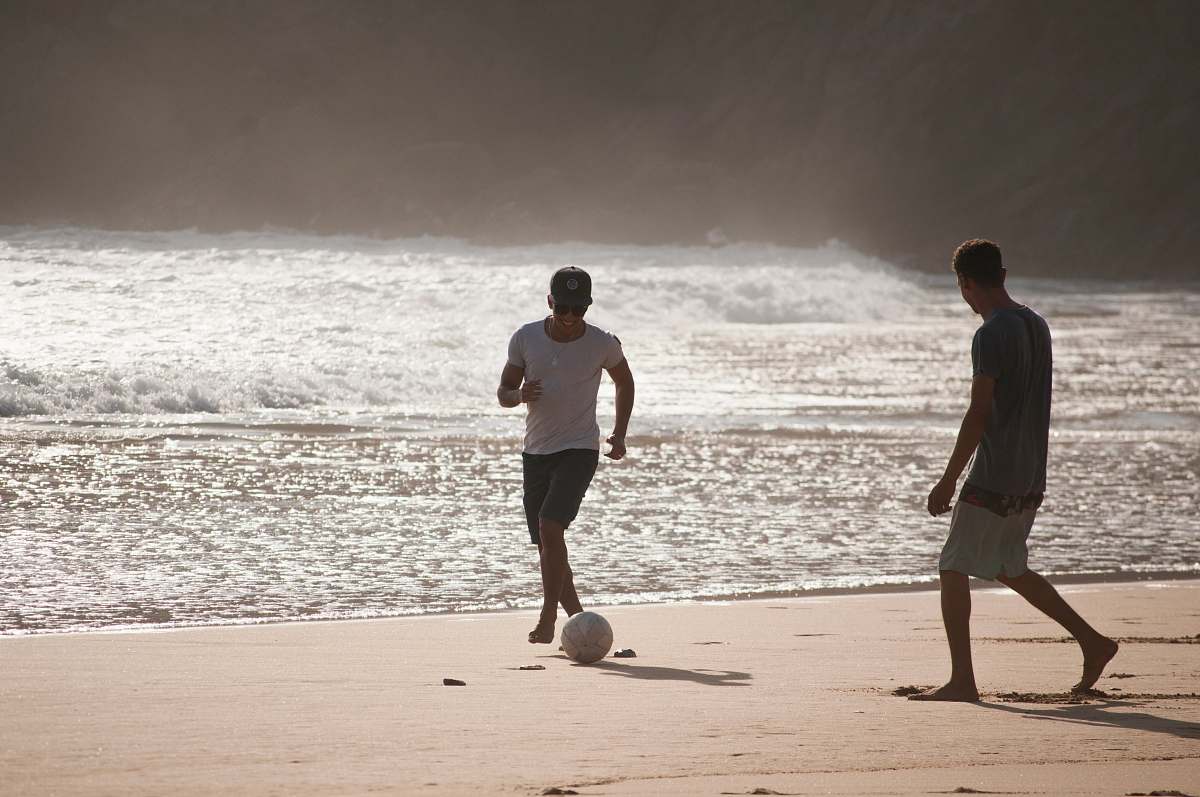 clothing men playing football in beach shorts