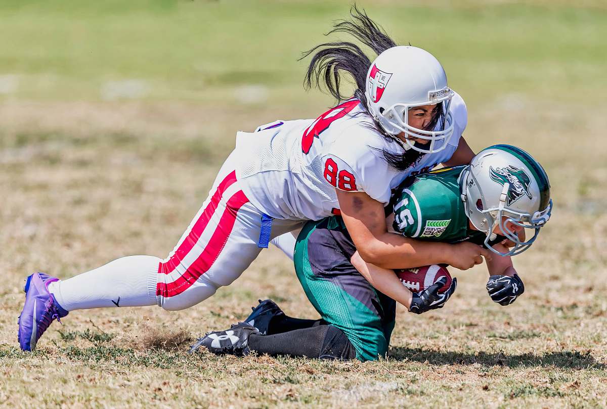 helmet player grabbing another player on ground during daytime clothing