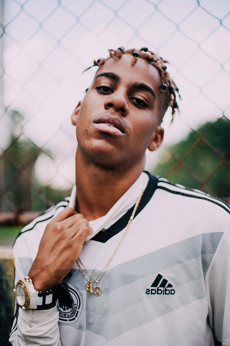 clothing selective focus photography of man wearing adidas Germany soccer jersey shirt beside link fence human