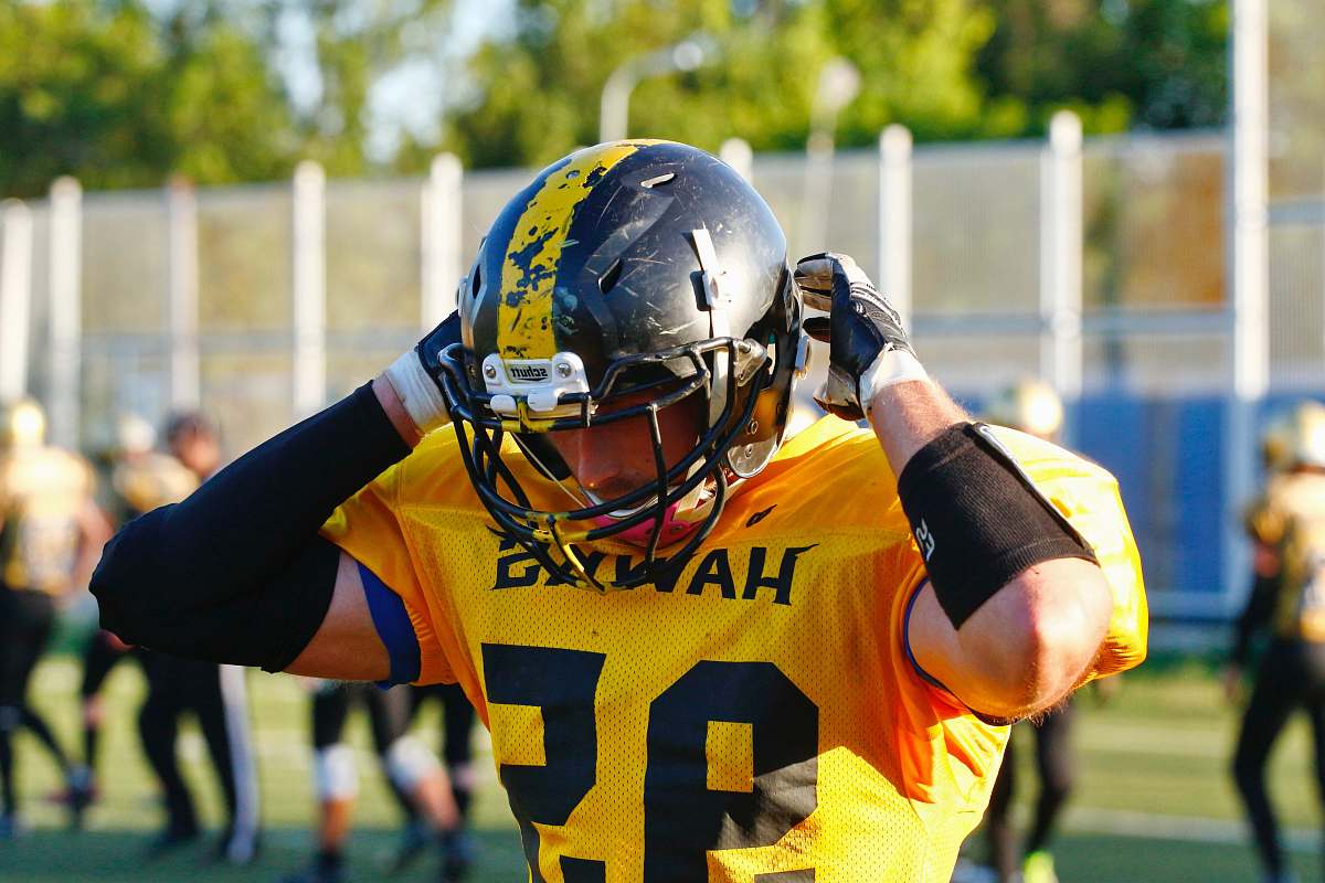 clothing shallow focus photo of man wearing yellow Hawks 95 football jersey helmet