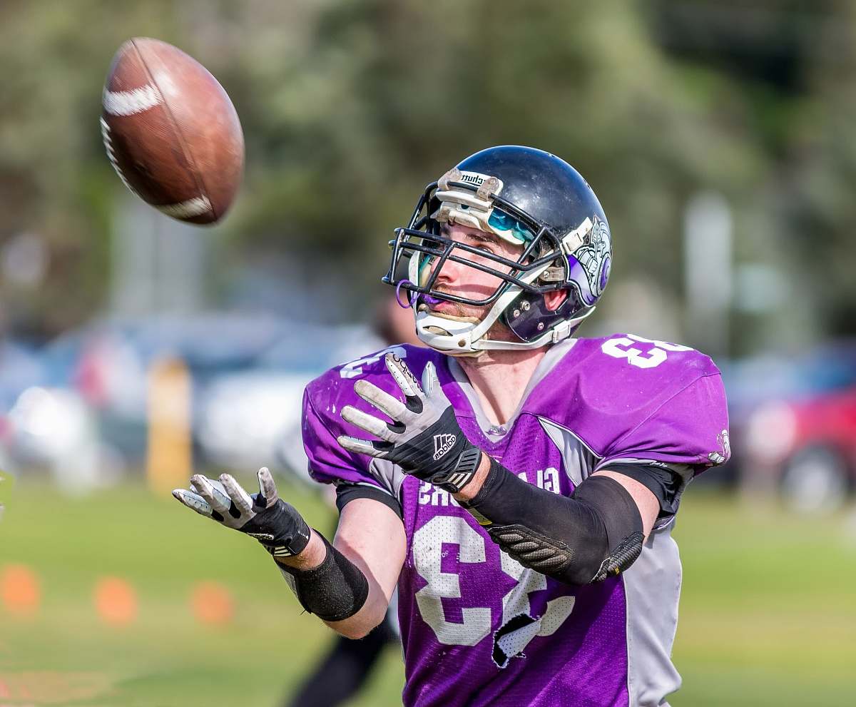 clothing time-lapse photography of a football player catching a ball helmet