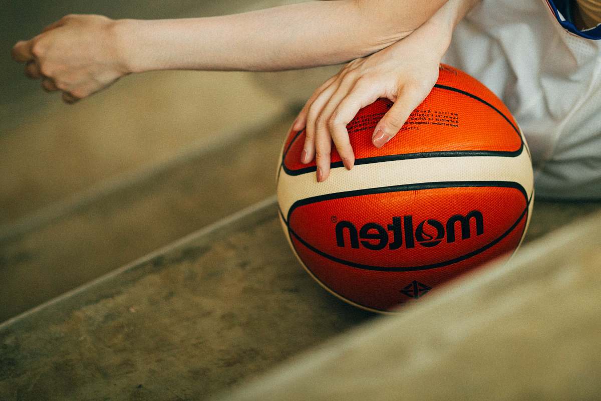 female person holding red and white Molten basketball ball woman
