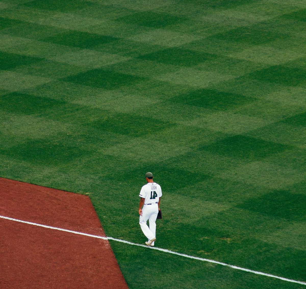 sport baseball player standing on field steps on white line at daytime sports