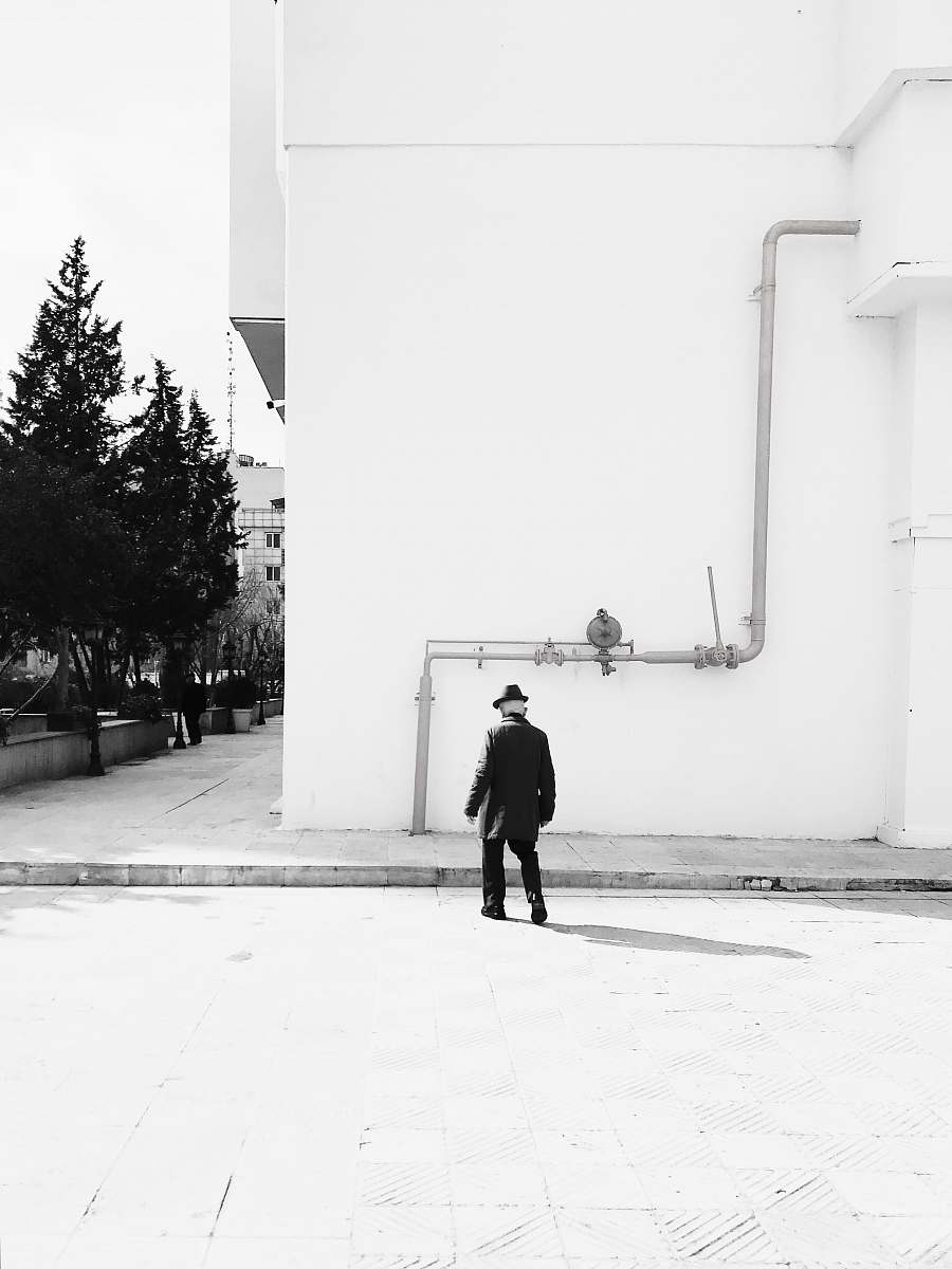 human man walking towards curb and building person