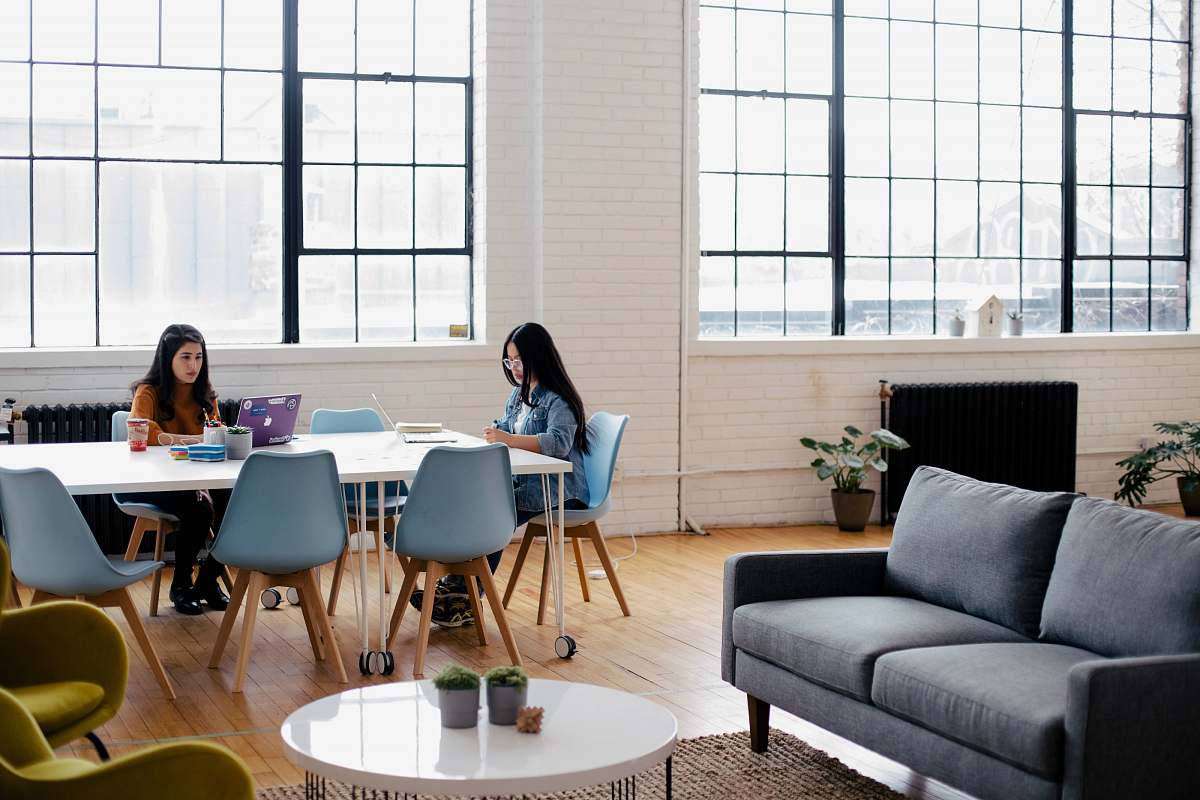 furniture two women sitting in front of white table couch