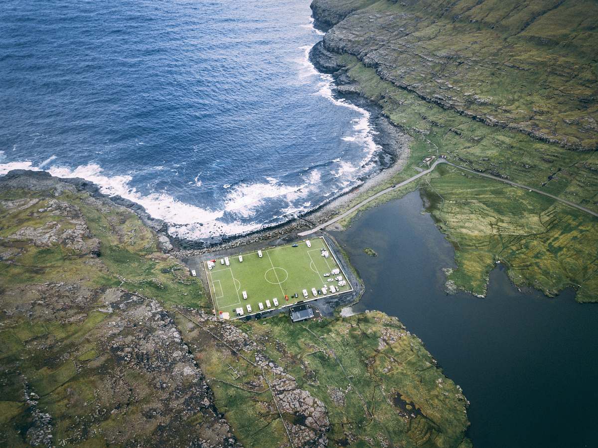 field aerial photo of soccer field near body of water during daytime team sport