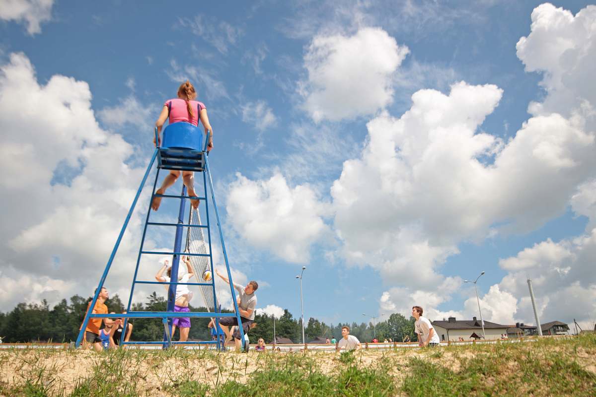 summer group of teens playing volleyball girl sitting on umpire's chair playing
