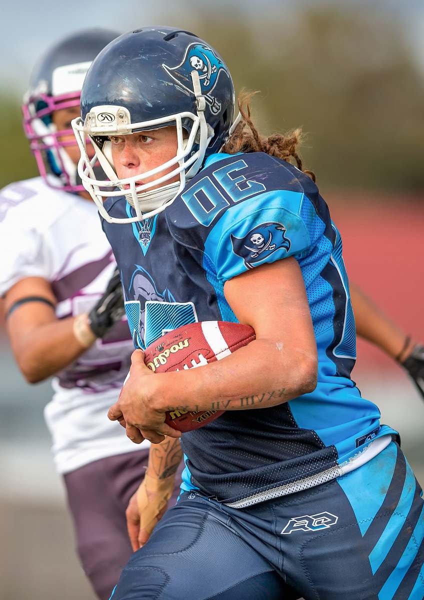apparel selective focus photography of woman in blue 30 jersey shirt holding brown football clothing