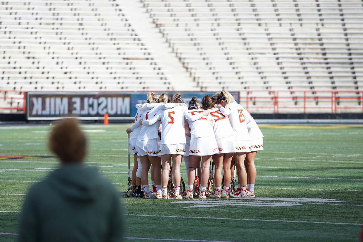 person all women lacrosse team on huddle at the field apparel