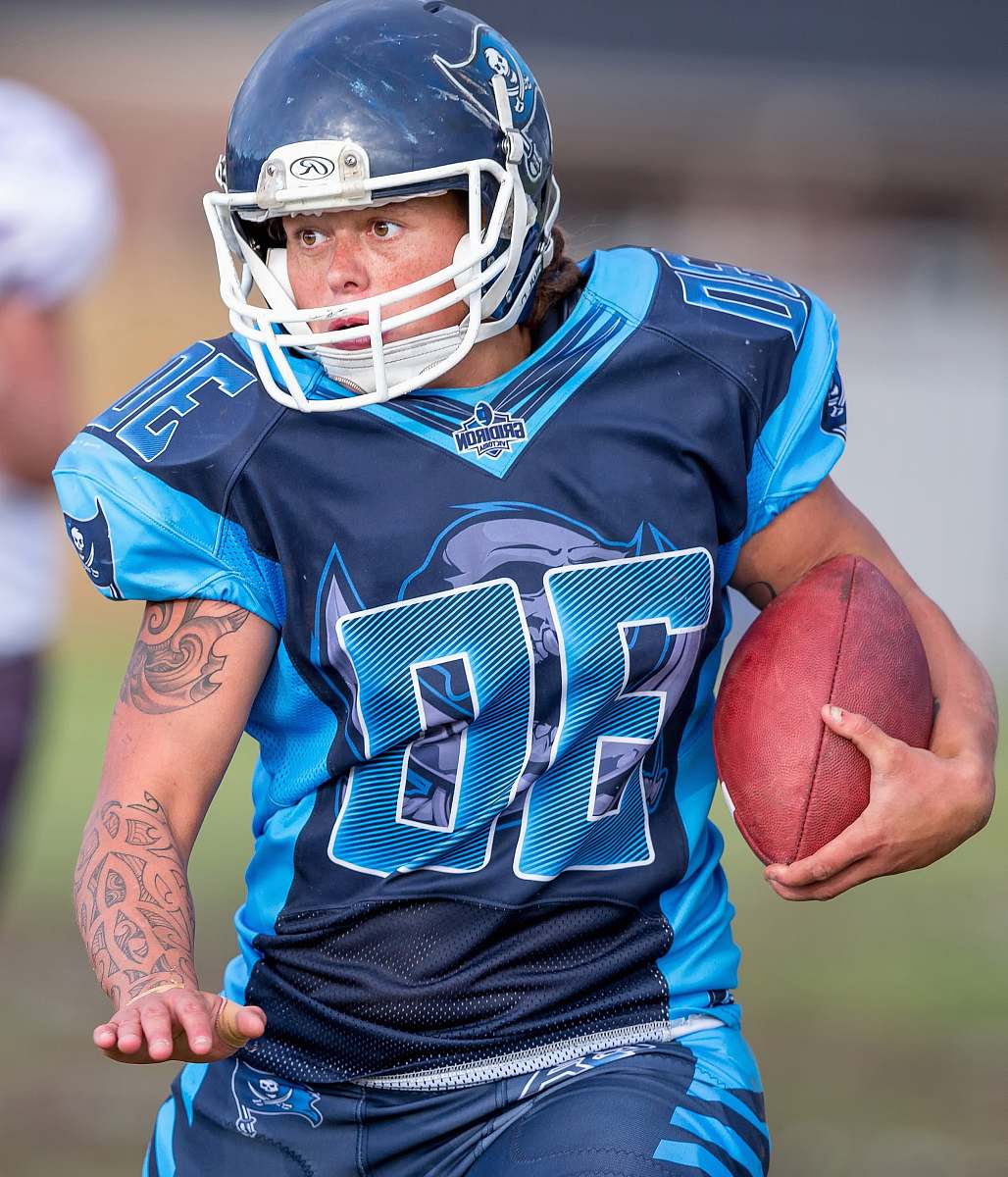 football focus photo of person playing football holding ball while running people