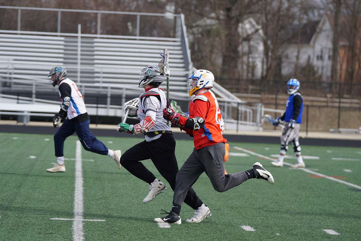 person four men playing lacrosse game during daytime apparel
