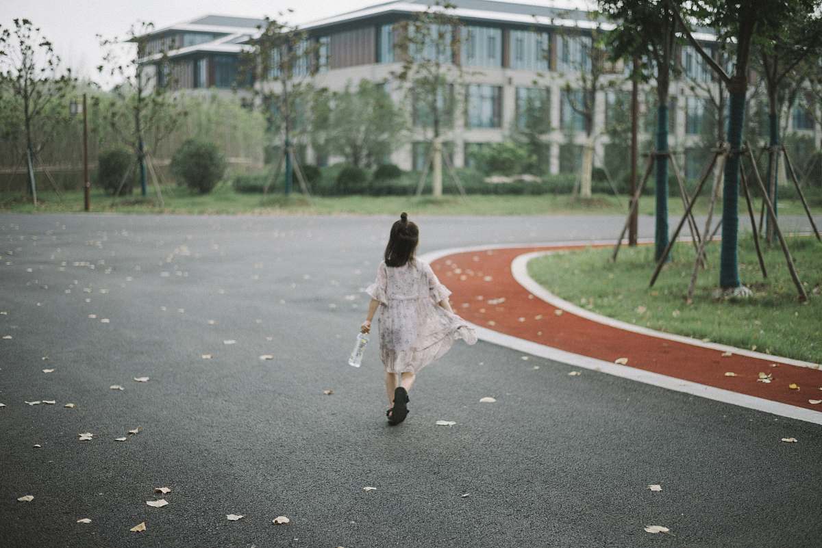 person girl holding clear plastic bottle walking on road people