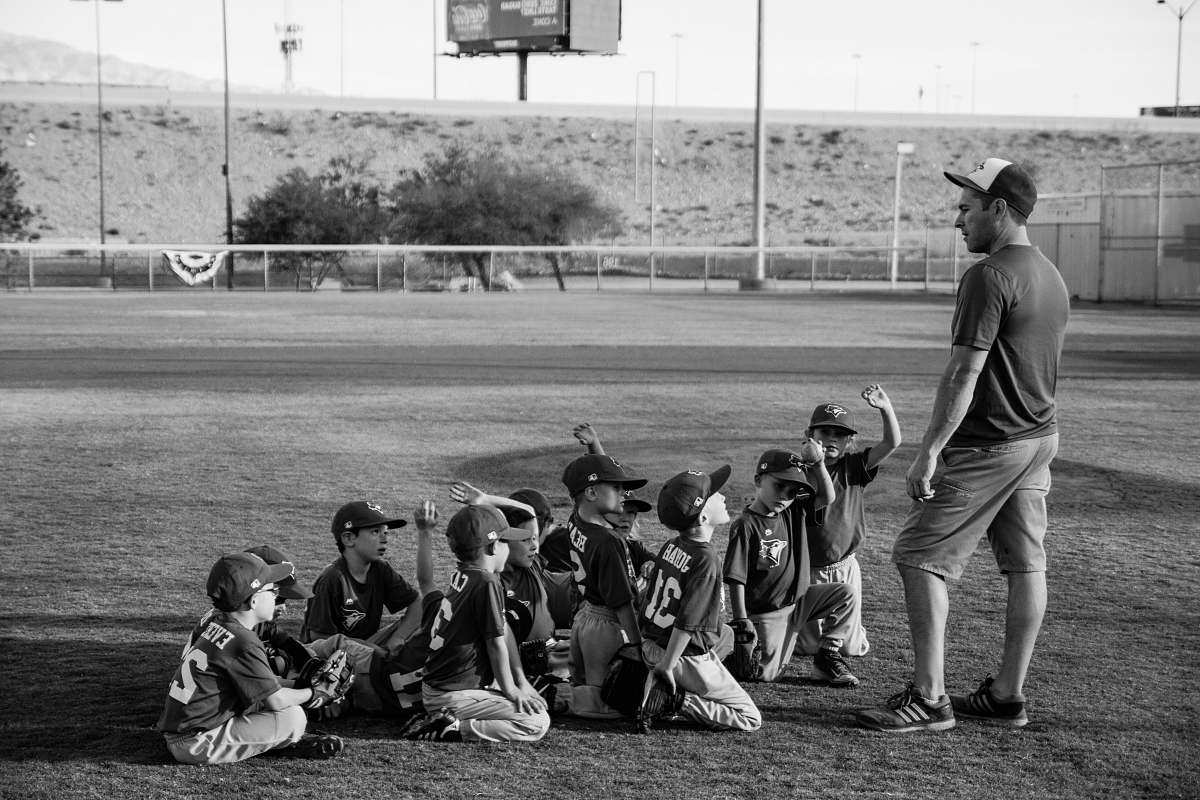 person grayscale photo of boys football team in front of coach black-and-white