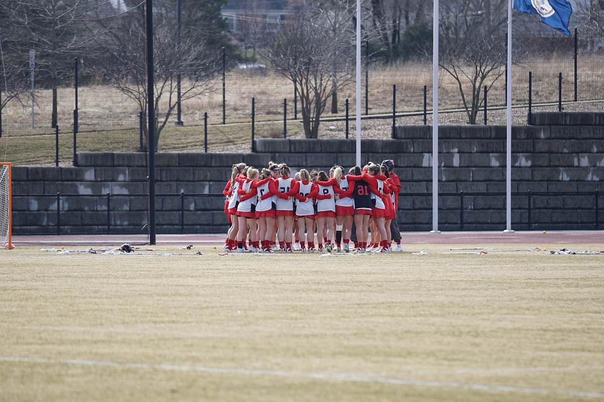 person group of girls in white-and-red top hugging on field during daytime crowd