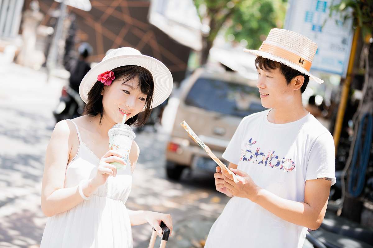person man and woman wearing hats holding disposable cups near vehicle during daytime people