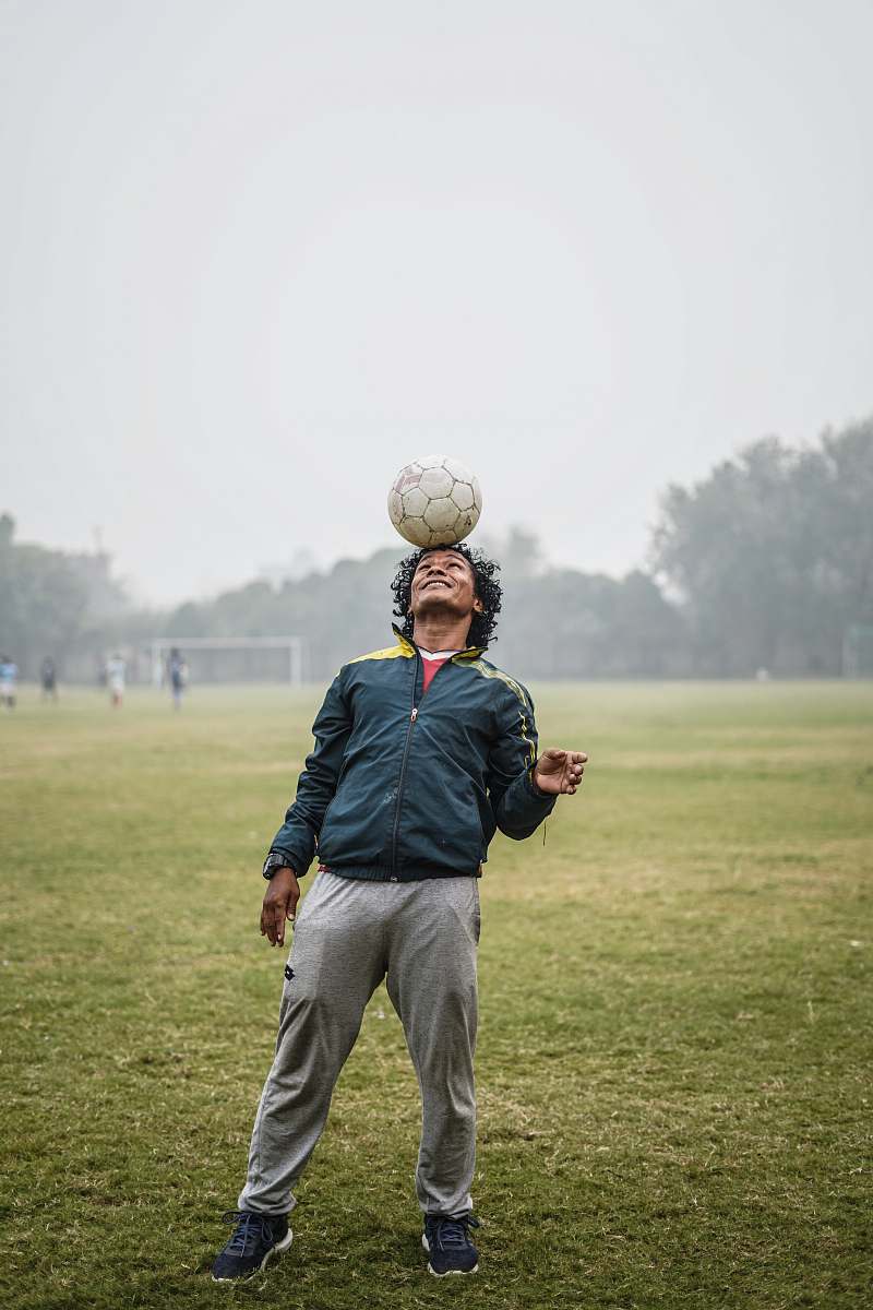 person man balancing a soccer ball on his head people