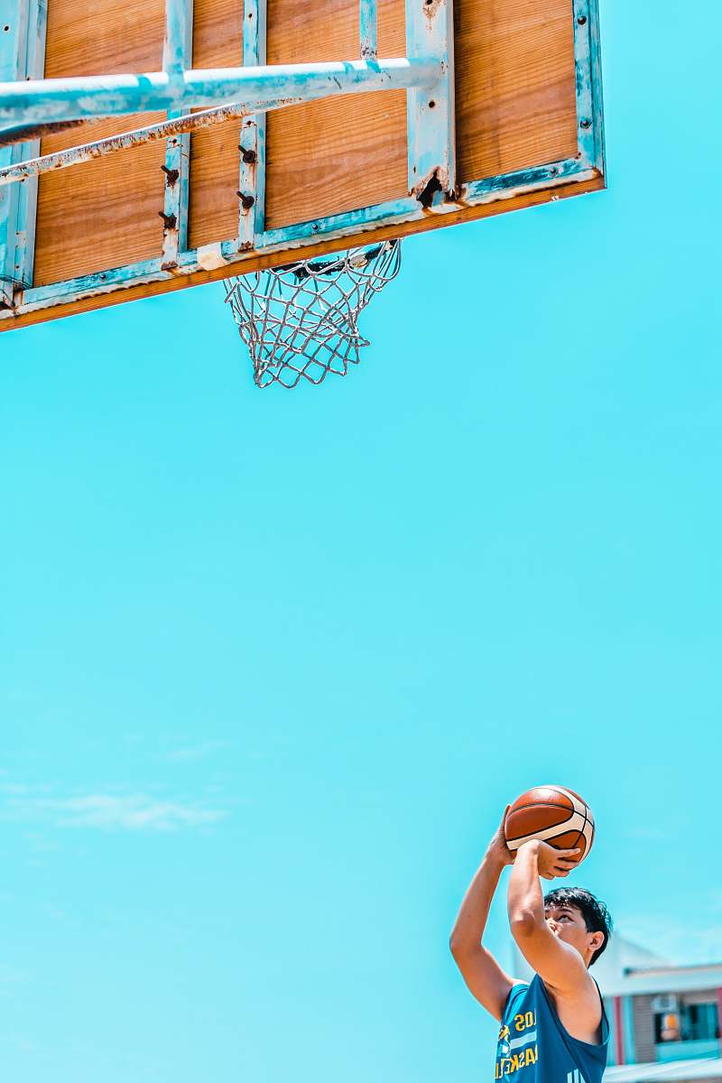 person man holding basketball in front of basketball system during daytime people
