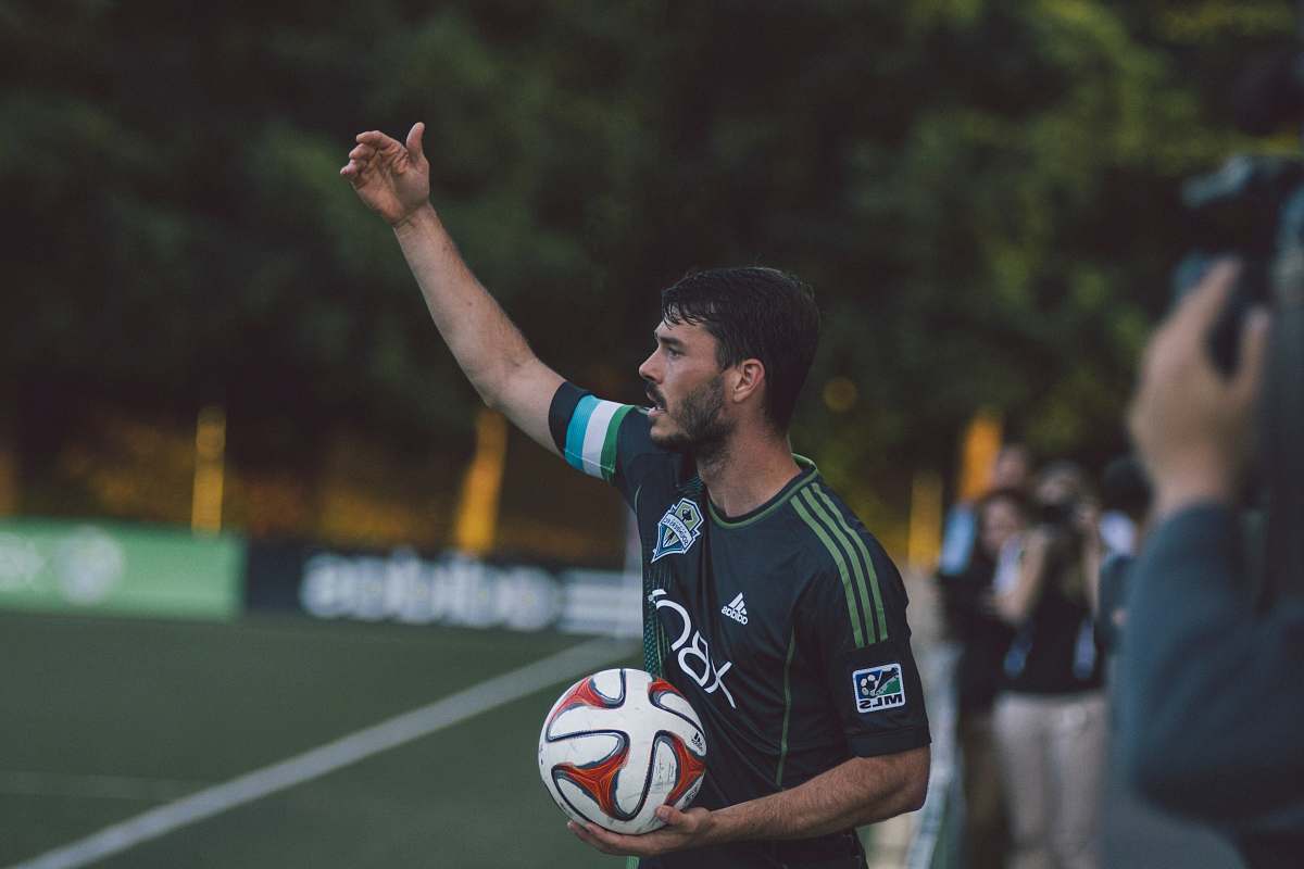 person man in black and green Adidas jersey shirt holding soccer ball soccer