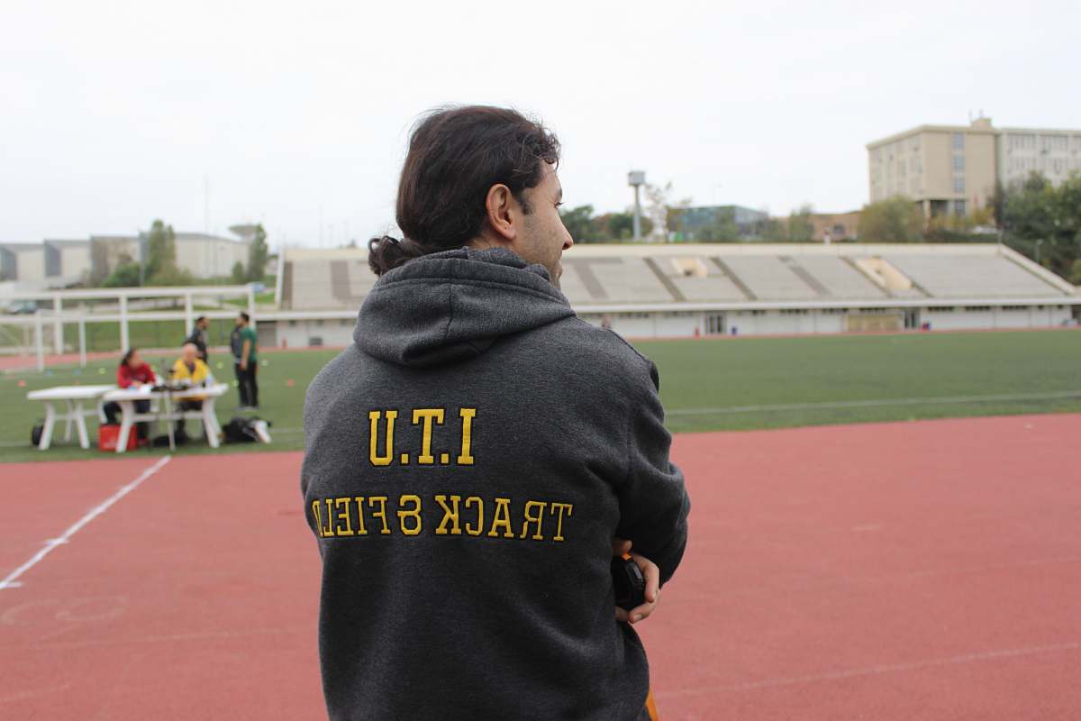 person man in black and yellow hoodie front of field people