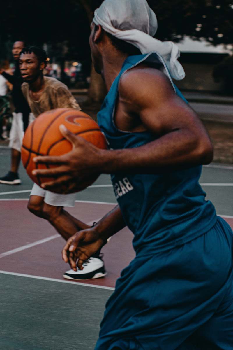 person man in blue basketball uniform with ball in court people