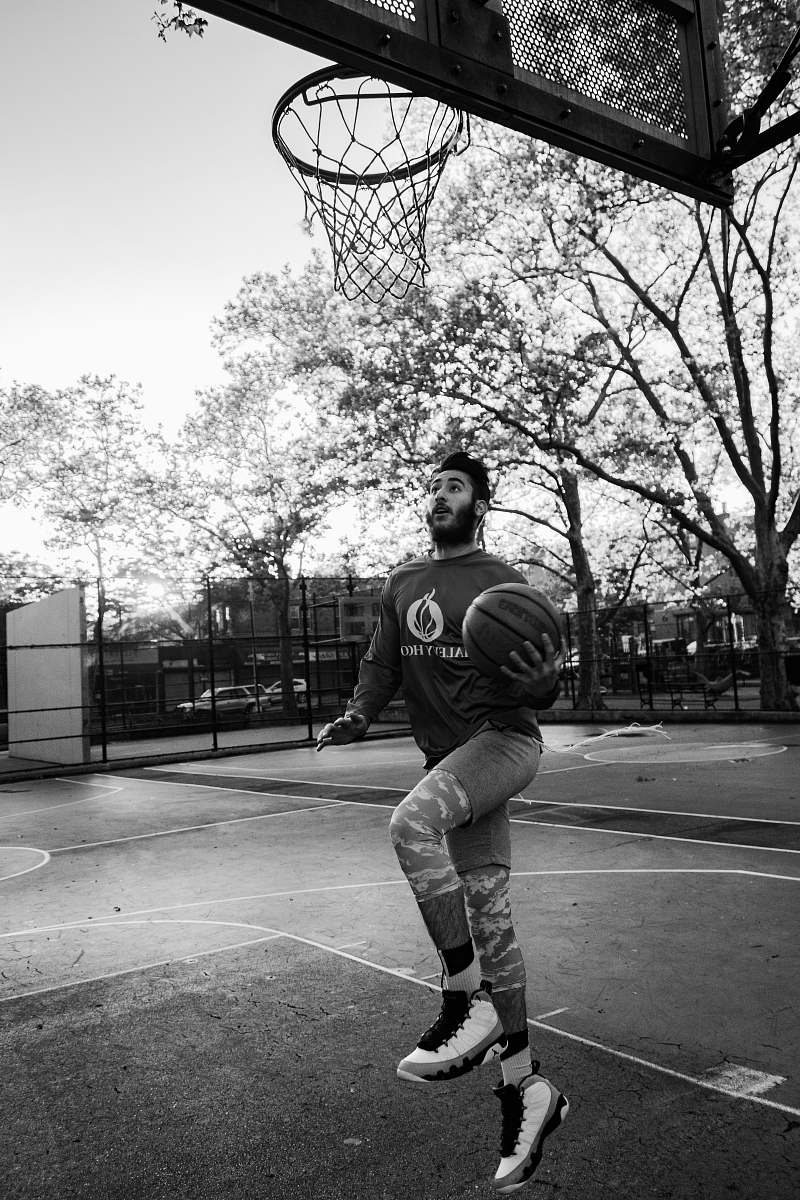 person man playing basketball on outdoor basketball court black-and-white