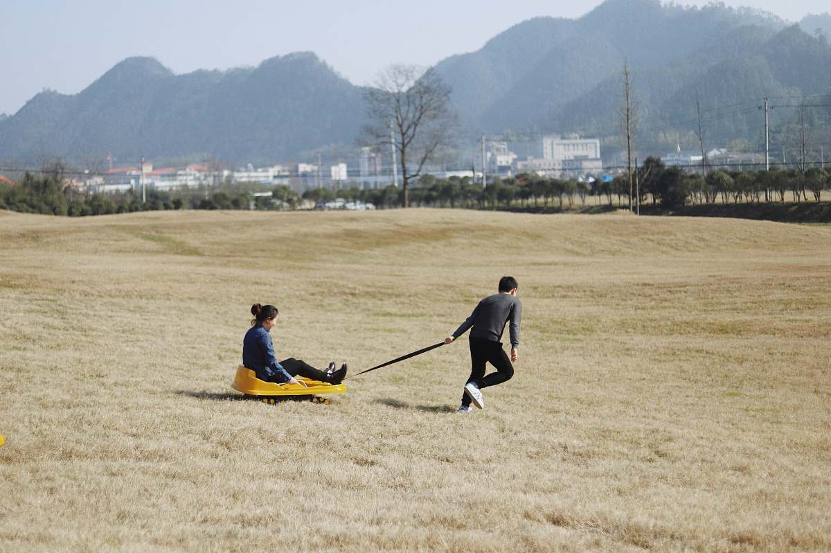 person man pulling wagon with woman riding on it people