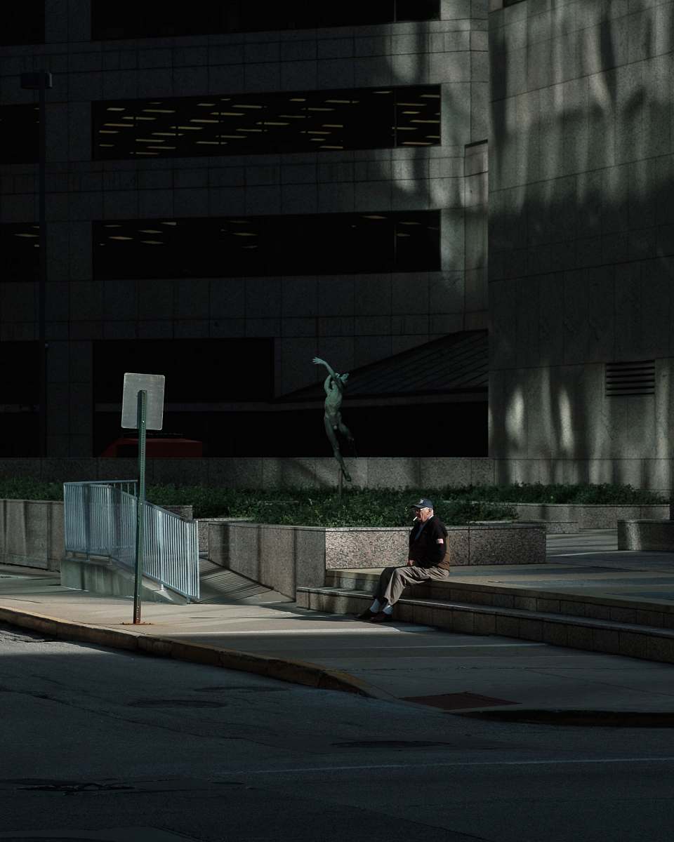 person man sitting on stairs outside building people
