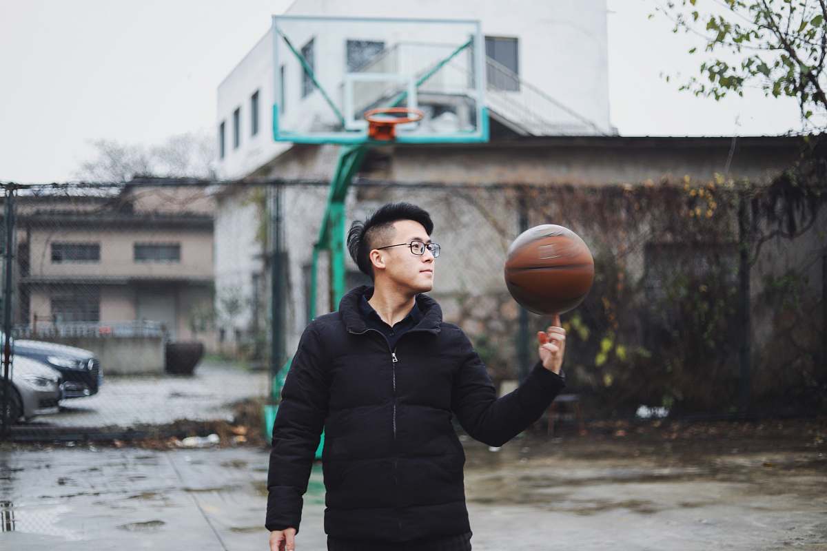 person man wearing black bubble zip jacket with basketball spinning on his right index finger people