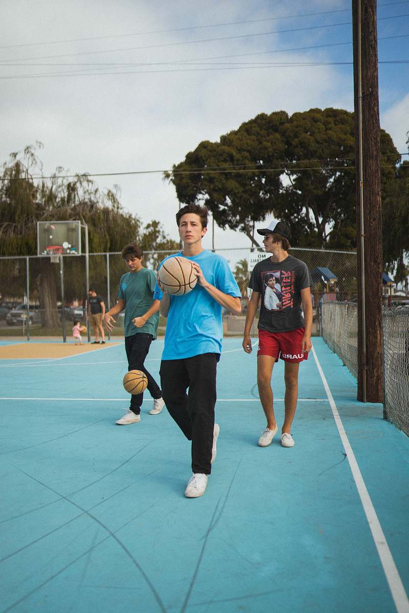 person man wearing blue t-shirt and black pants holding basketball during daytime apparel