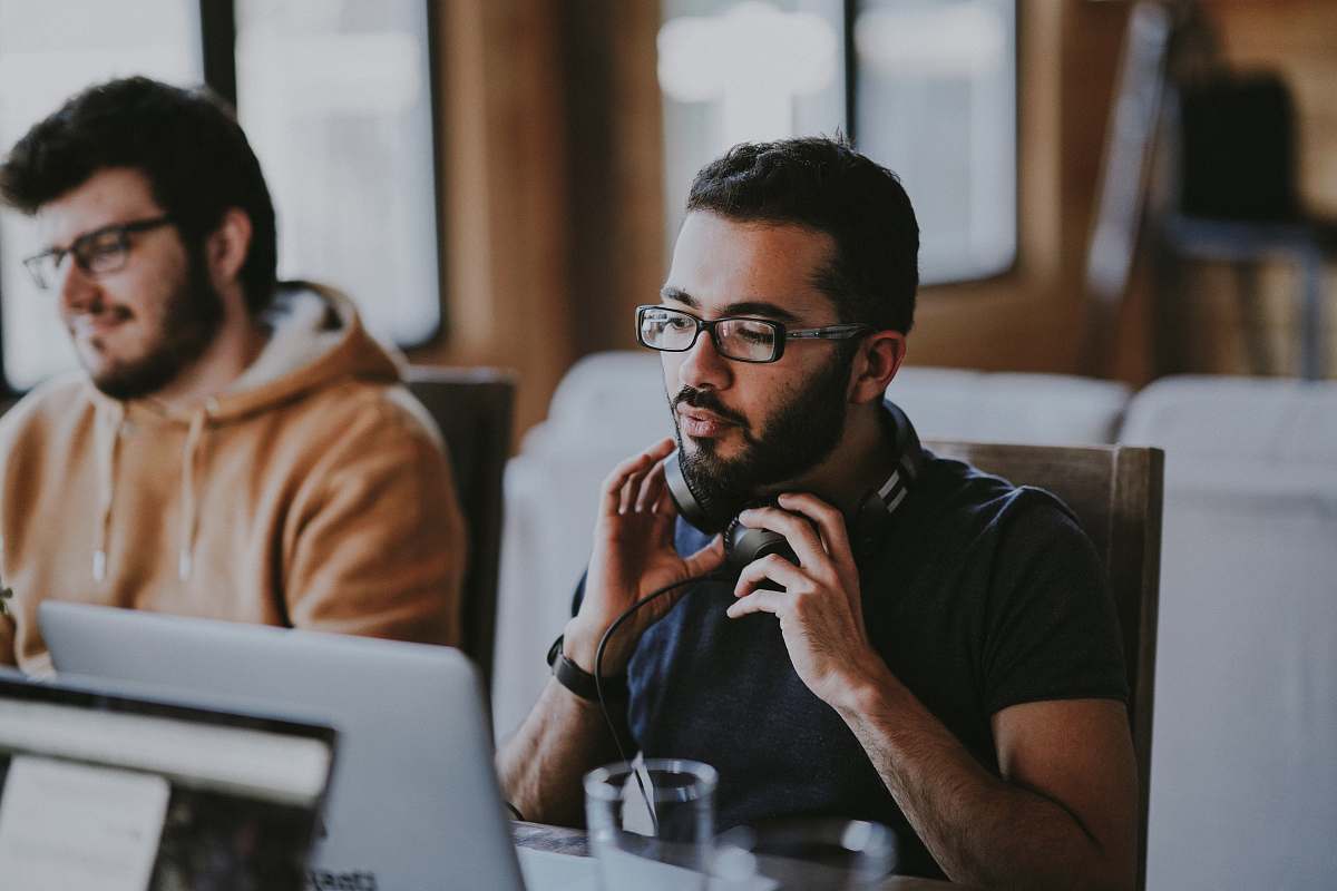 person man wearing eyeglasses and headphones beside smiling man people