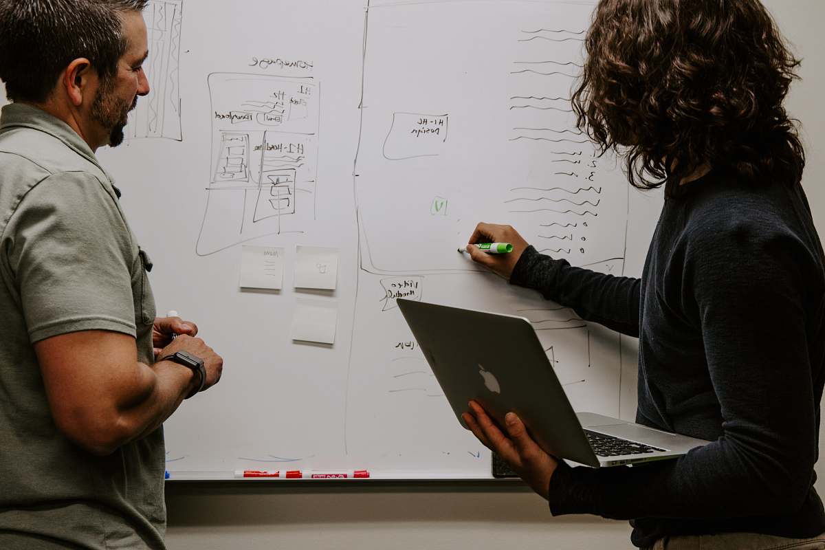 person man wearing gray polo shirt beside dry-erase board people