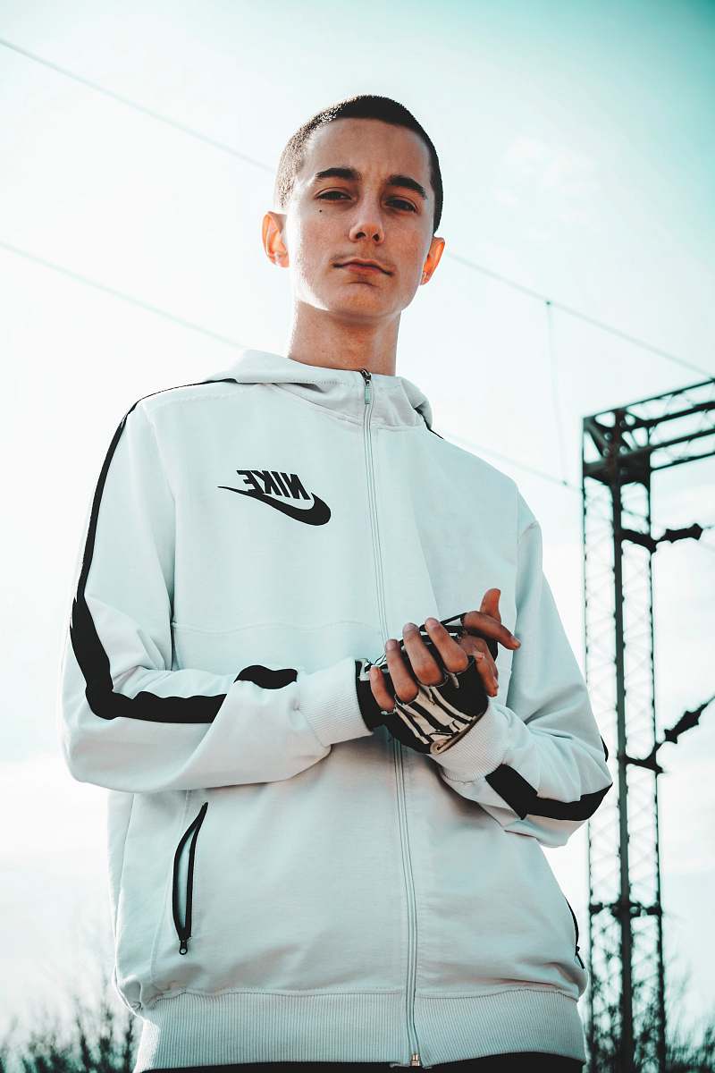 apparel man wearing white and black full-zip Nike hoodie standing across electric cable wires clothing