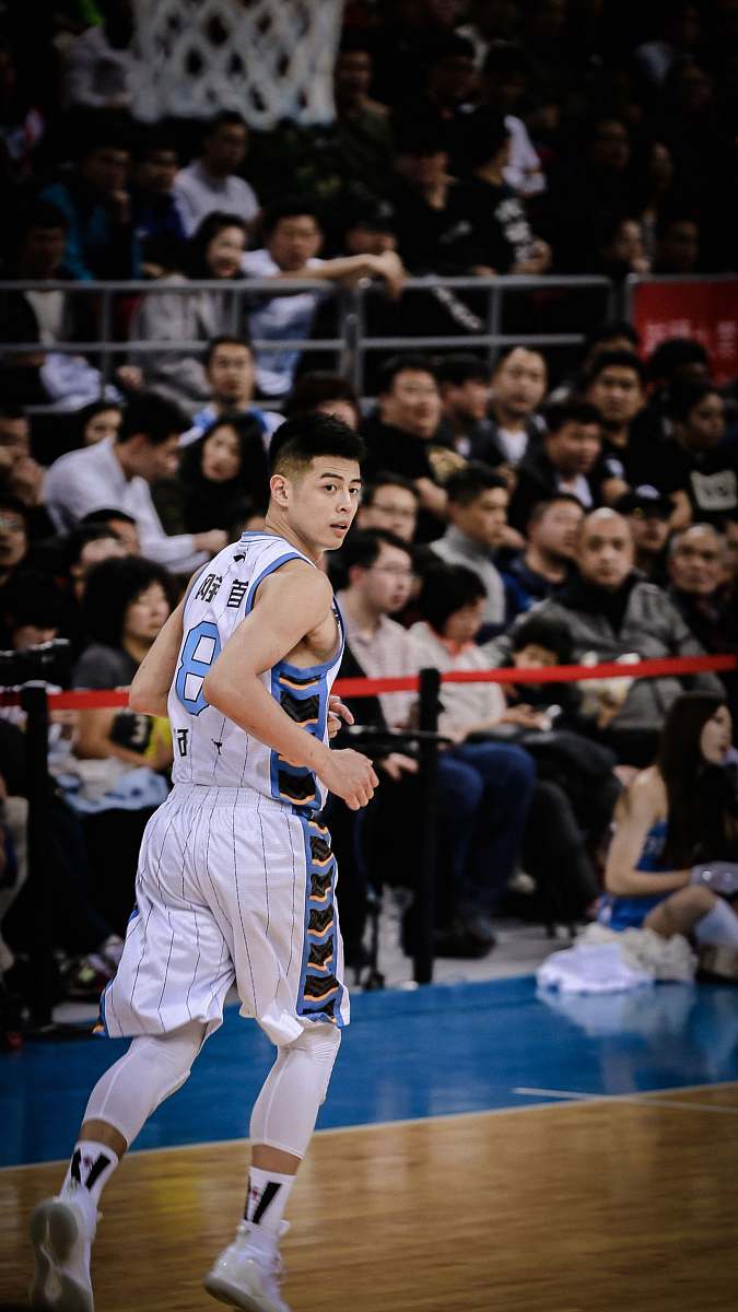 people man wearing white and blue basketball jersey standing inside basketball field basketball