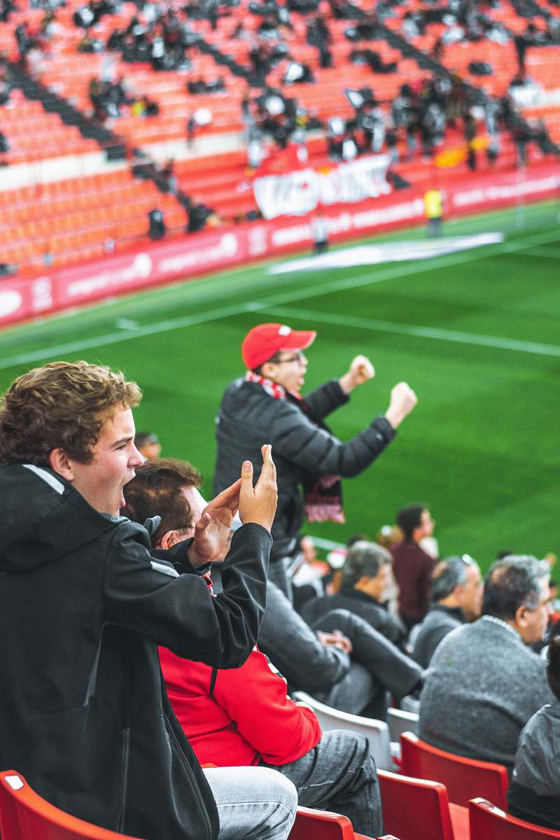 person men at bleachers cheering on players on a sports field people