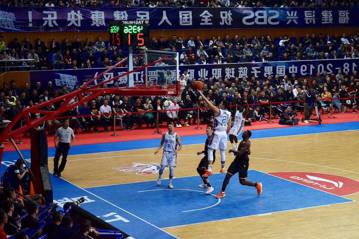 person men playing basketball game surrounded with people watching people