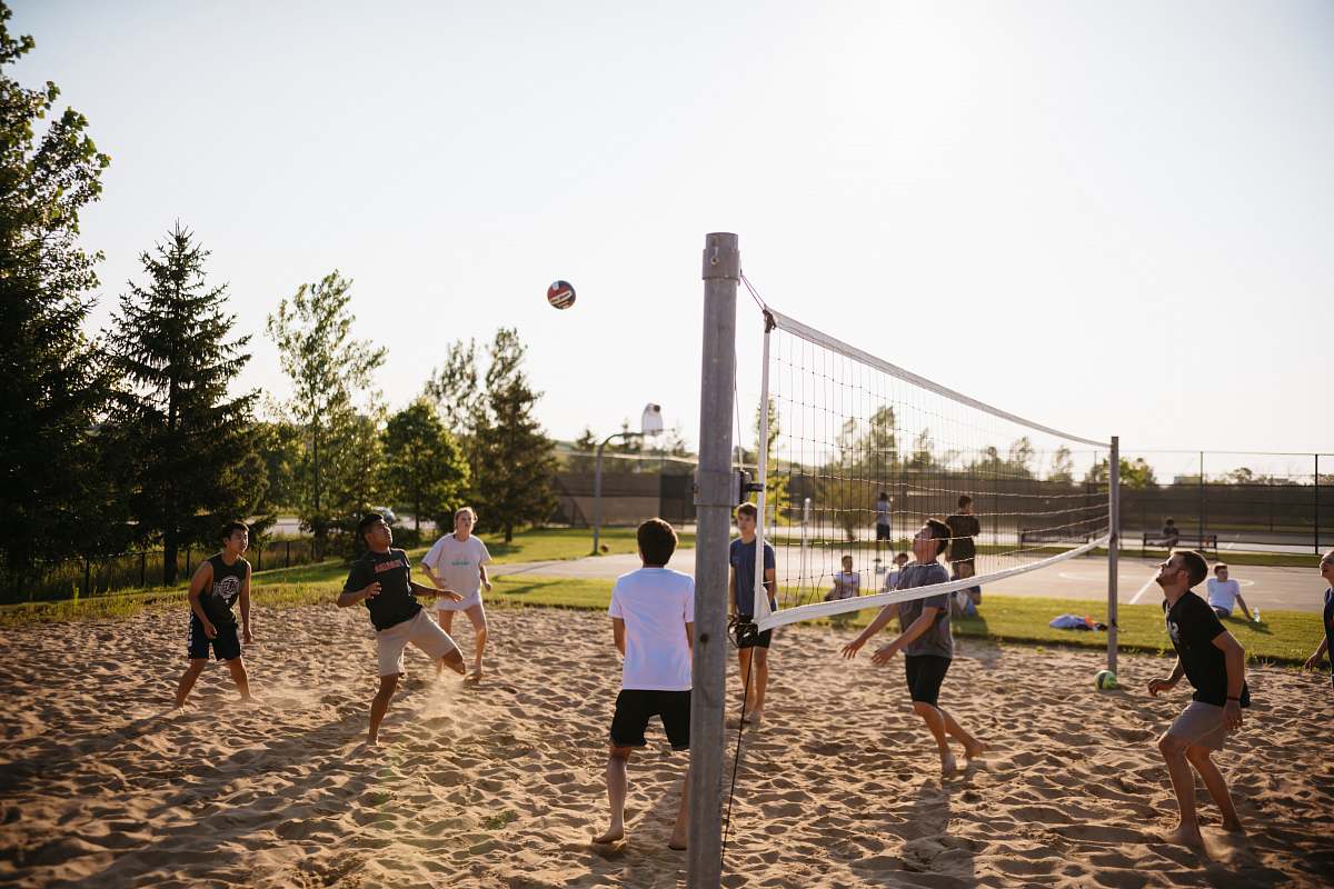 person men playing volleyball near pine trees team sport