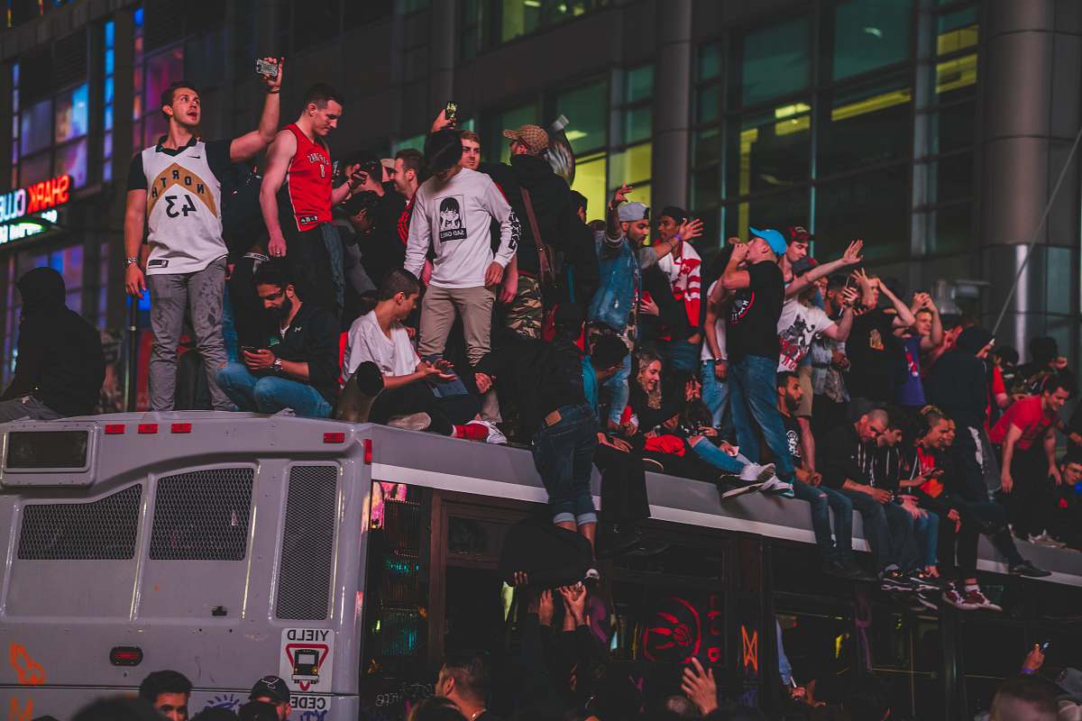 Capture the vibrant energy of passionate Toronto Raptors fans as they cheer from the rooftop of a shed during a thrilling nighttime game against the San Francisco 49ers at Rogers Field. This dynamic scene, set against a backdrop of excitement and camaraderie, is perfect for sports marketing, event promotion, or storytelling about community spirit and sports culture.