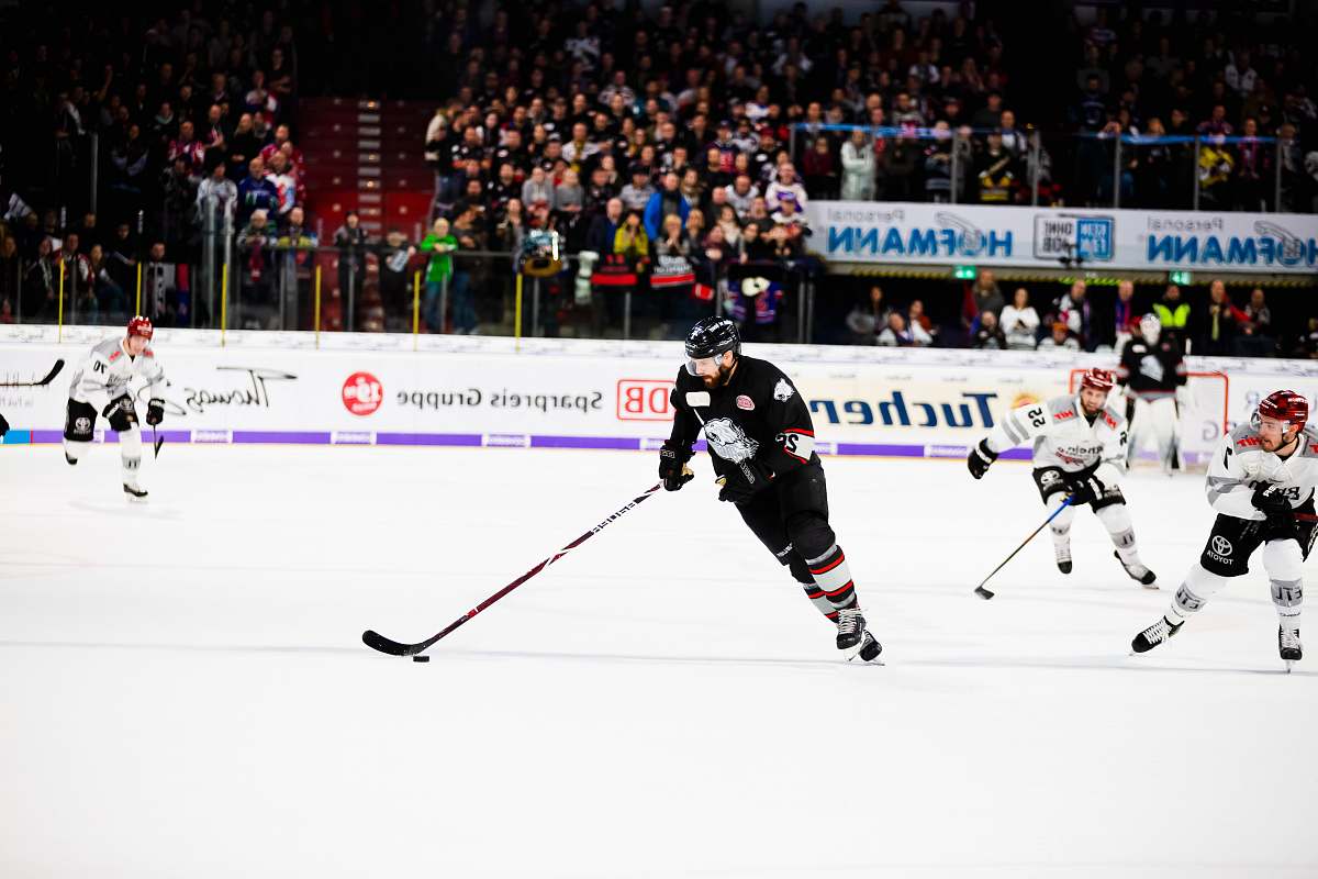 sports people playing hockey on field near people watching team