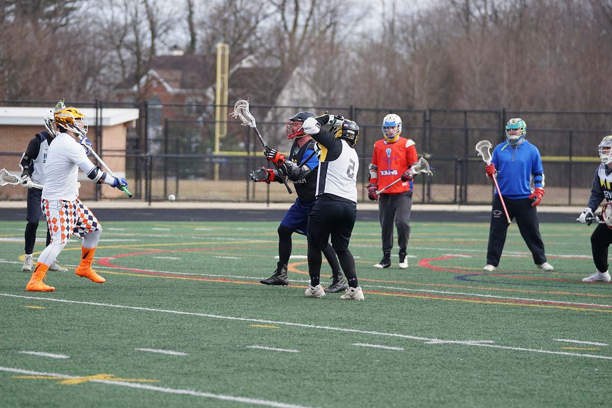 person people playing lacrosse on green grass field people