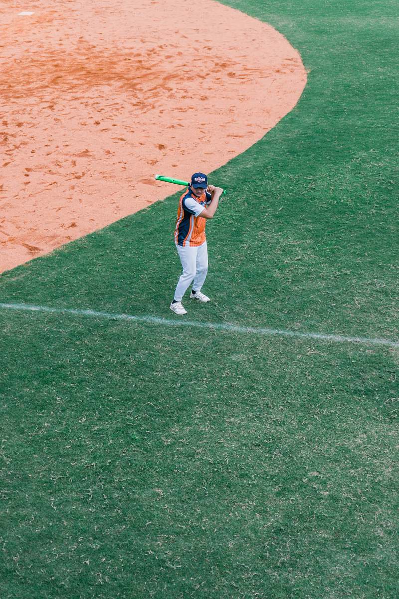 person person holding baseball bat on green field apparel