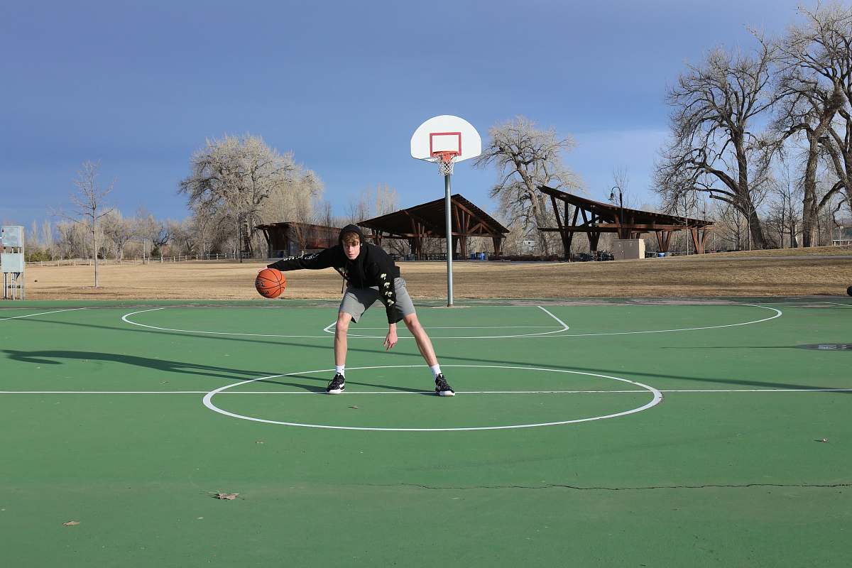 person person playing basketball on basketball court during daytime people