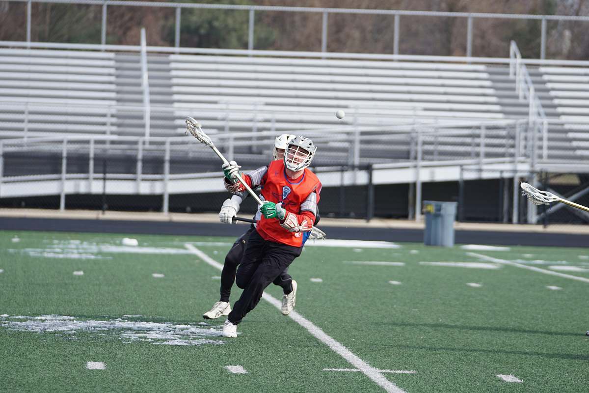person person wearing orange shirt playing lacrosse on field people