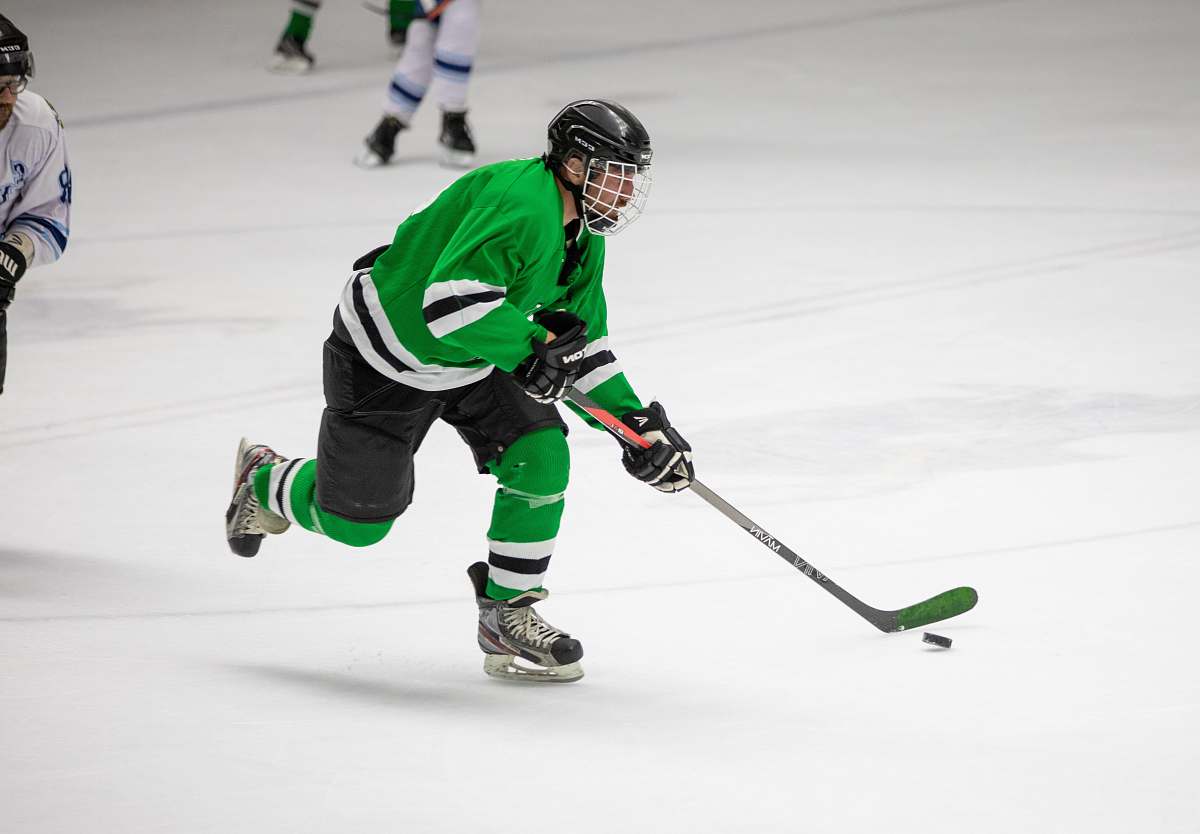 person photography of man in green jersey shirt playing hockey apparel