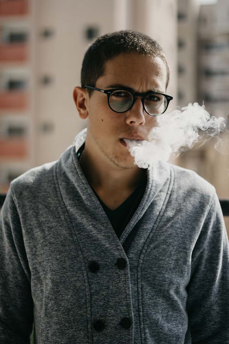 person selective focus photo of man smoking cigarette during daytime people