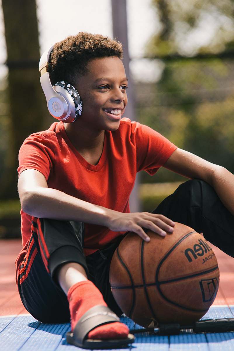 person selective focus photography of smiling boy wearing headphones and holding basketball people