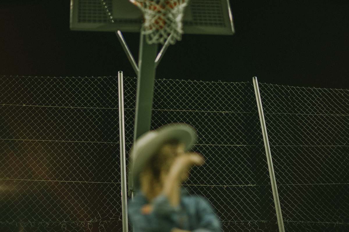 person selective focus photography of woman wearing gray hat on basketball court people
