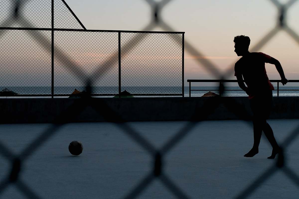 person silhouette of person by ball near sea during golden hour sport