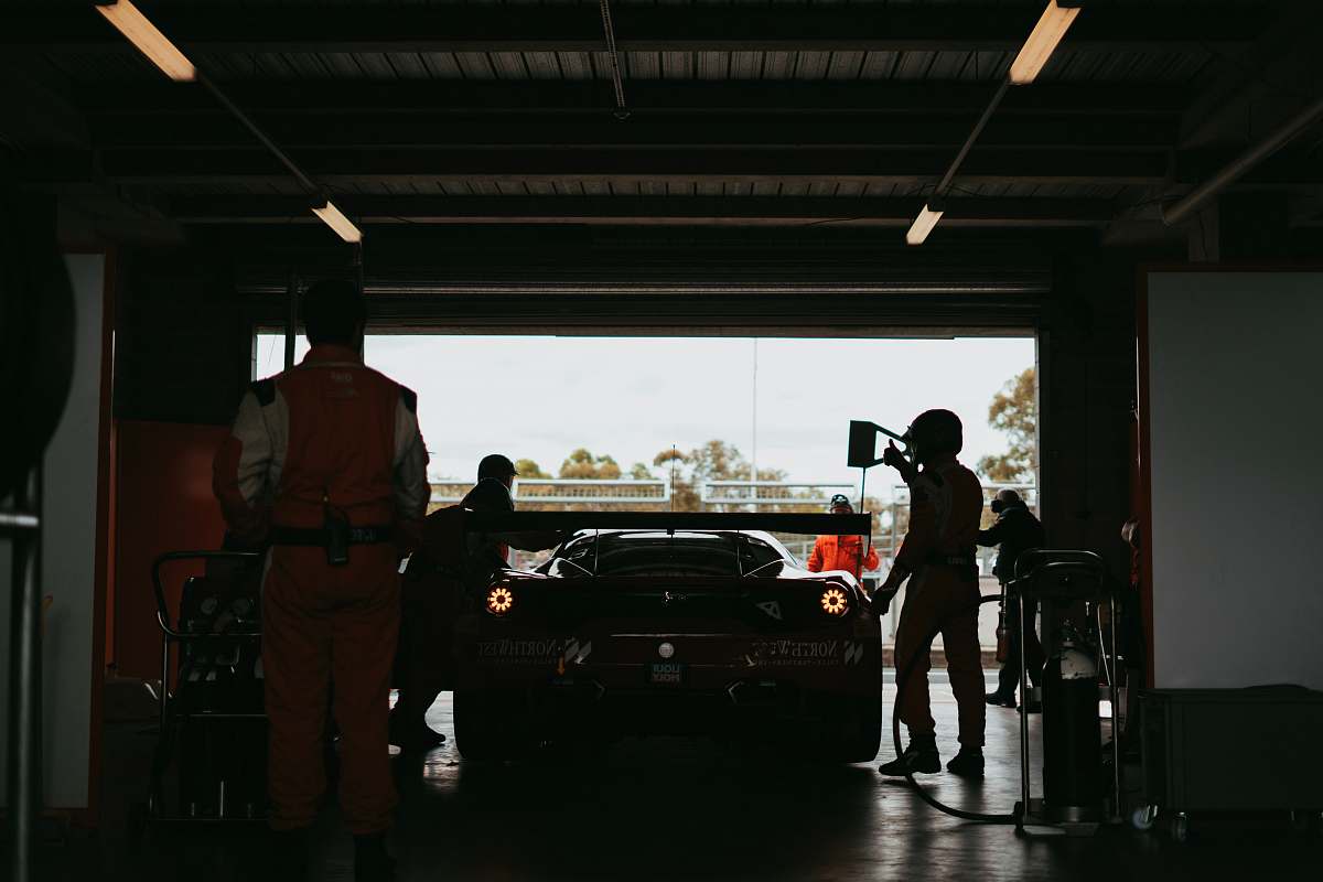 person silhouette photo of men standing front of car inside garage car