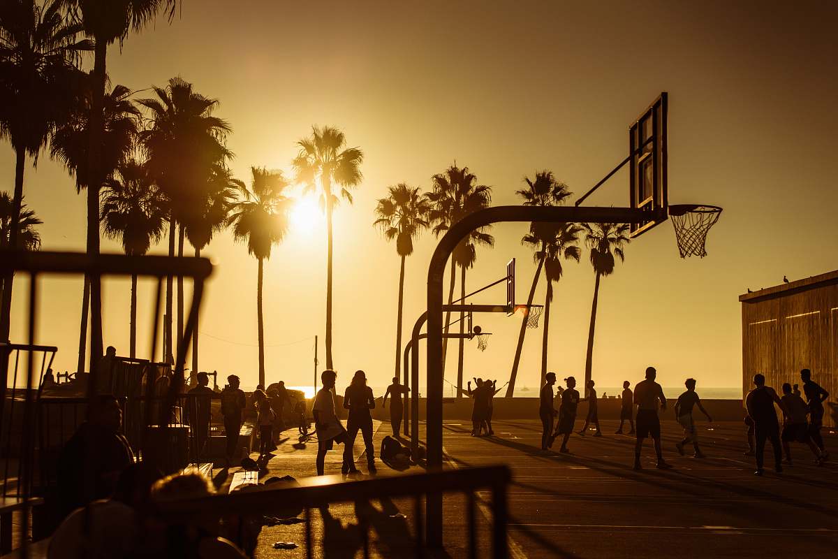 person silhouette photo of people in basketball court during golden hour people
