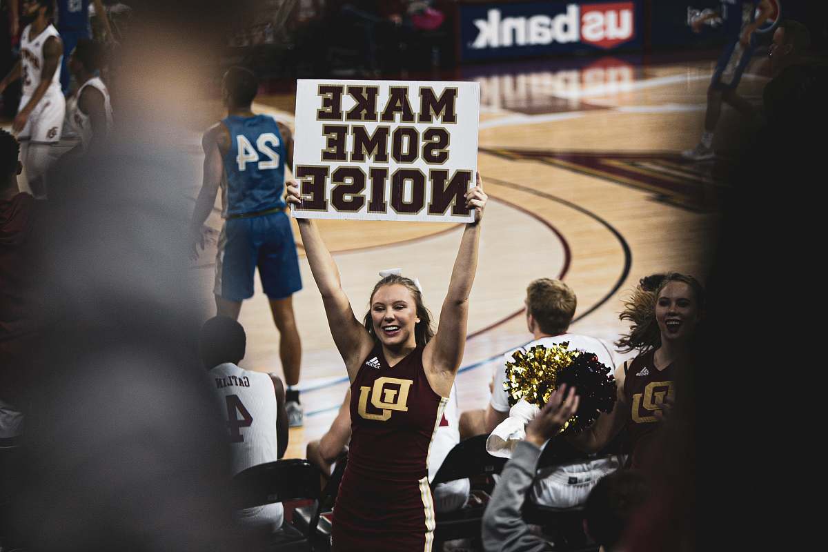person smiling woman standing while holding banner with make some noise print people